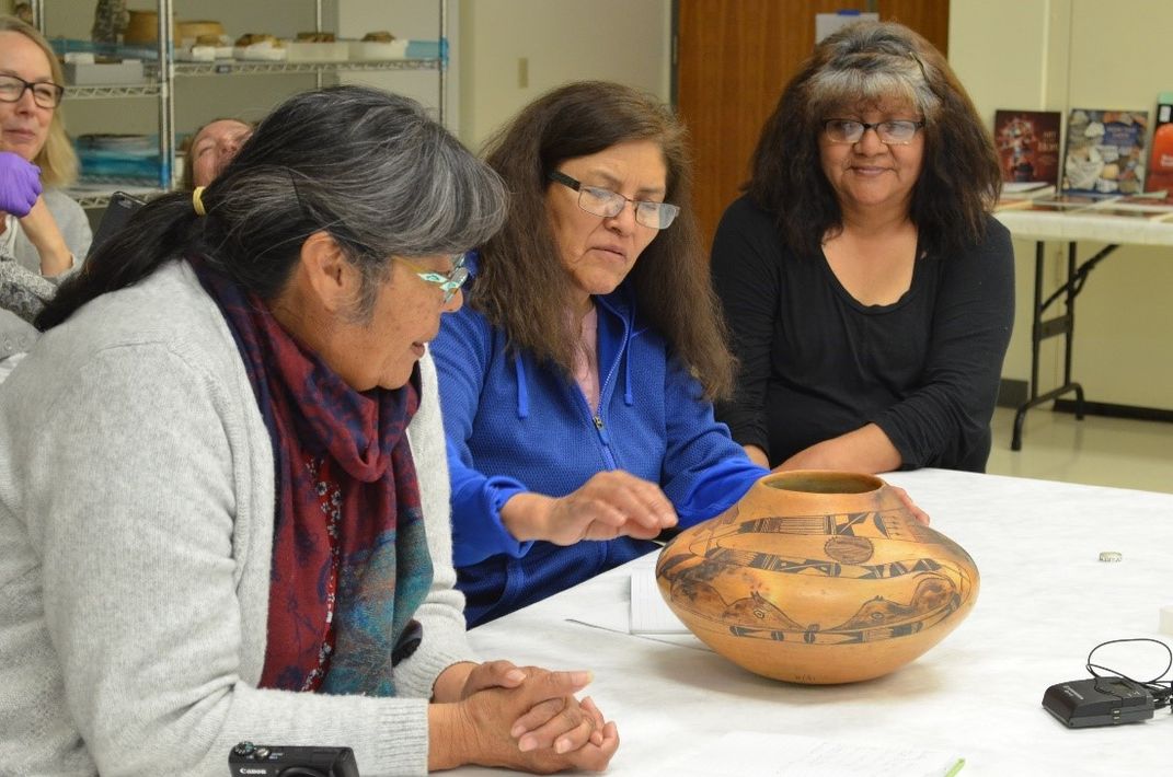 People sitting at a table with indigenous pottery.